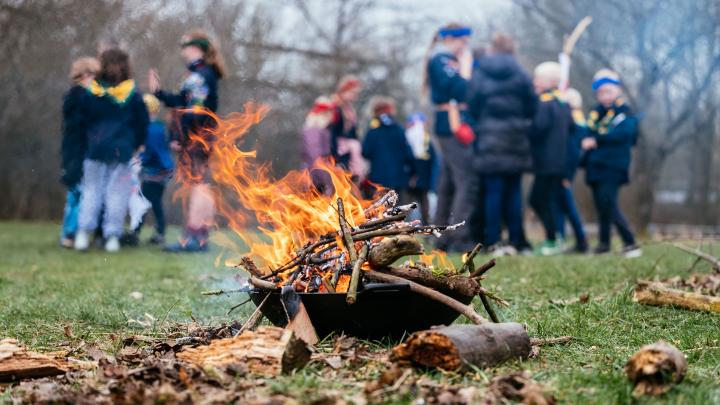 Bål i bålfad med spejdere ibaggrunden